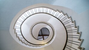 A spiral staircase with a central open area and a circular skylight.