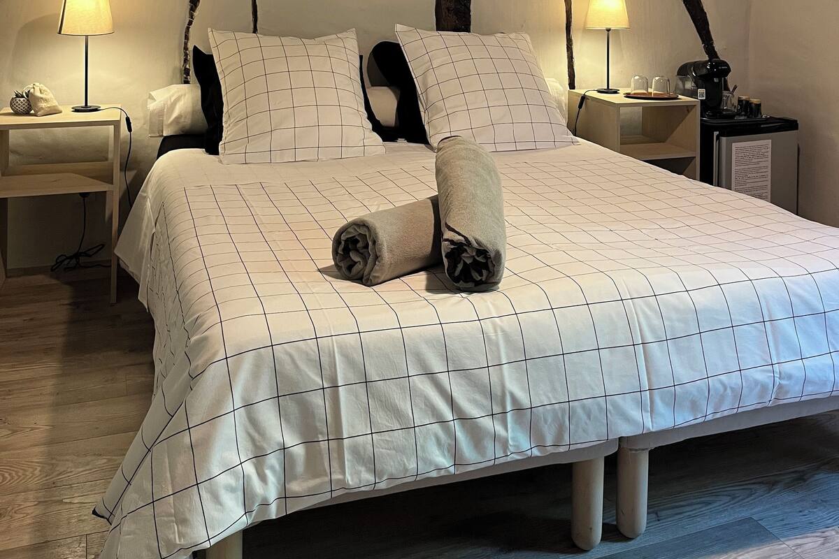 Une chambre à coucher avec un grand lit, deux tables de chevet avec des lampes et un plafond en bois.