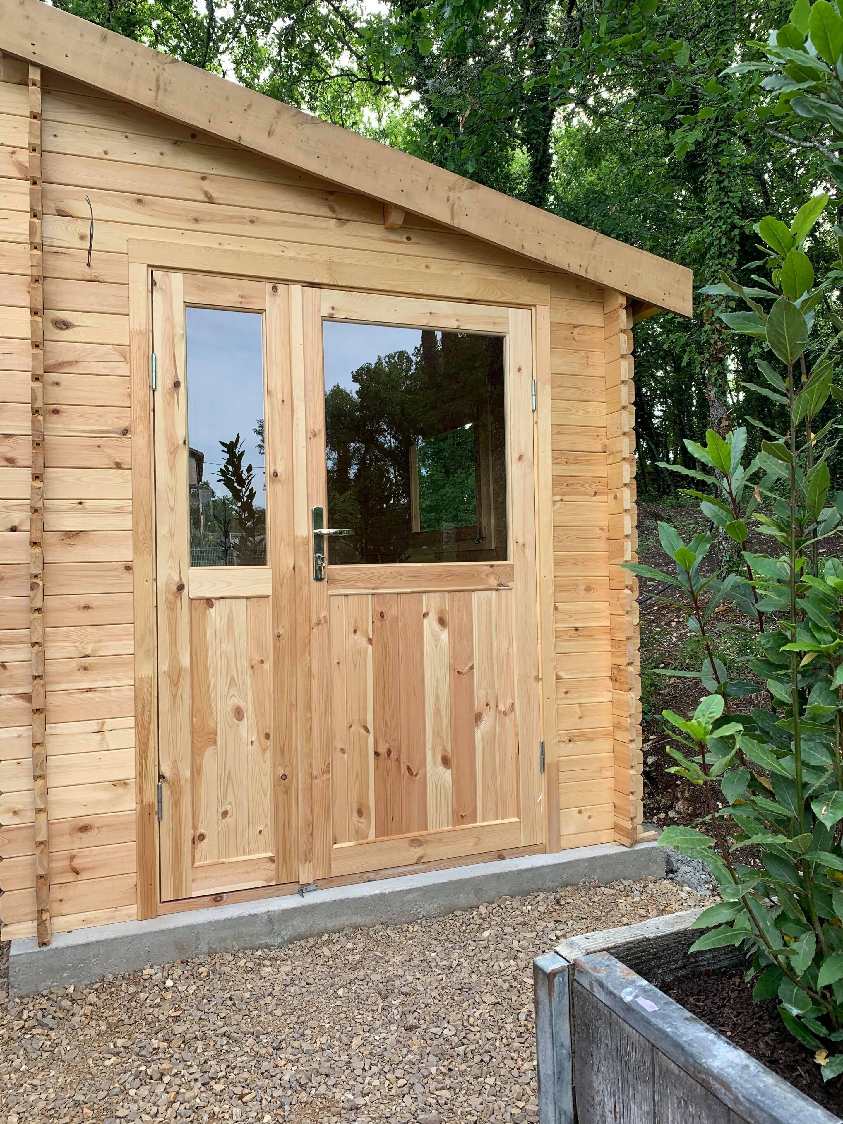 Een houten hut met een grote schuifdeur en een klein raam.