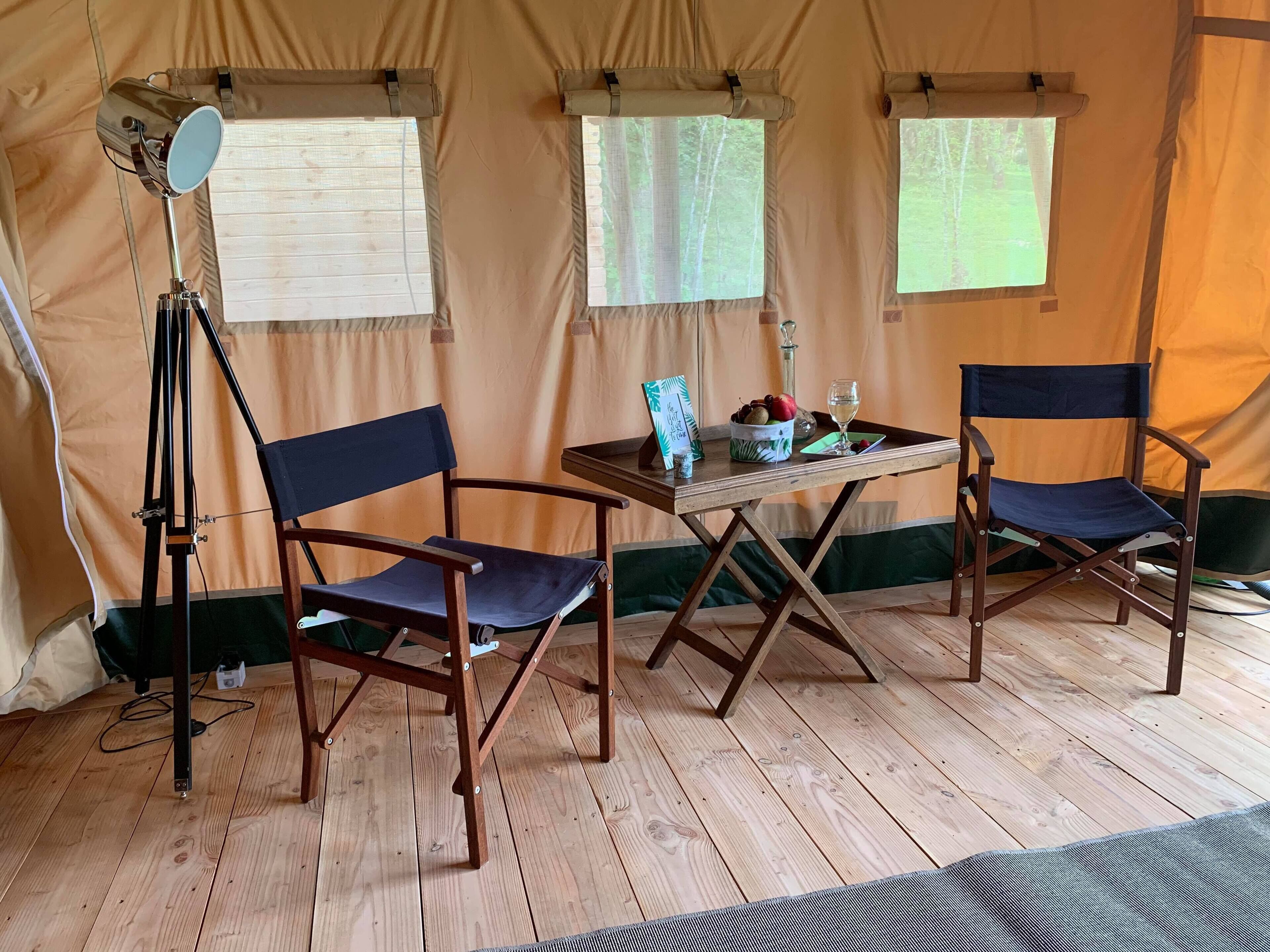 A tent with two chairs, a table, and a floor lamp.