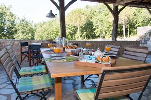 Enjoy breakfast in the serene outdoor dining area, surrounded by lush greenery and comfortable seating.