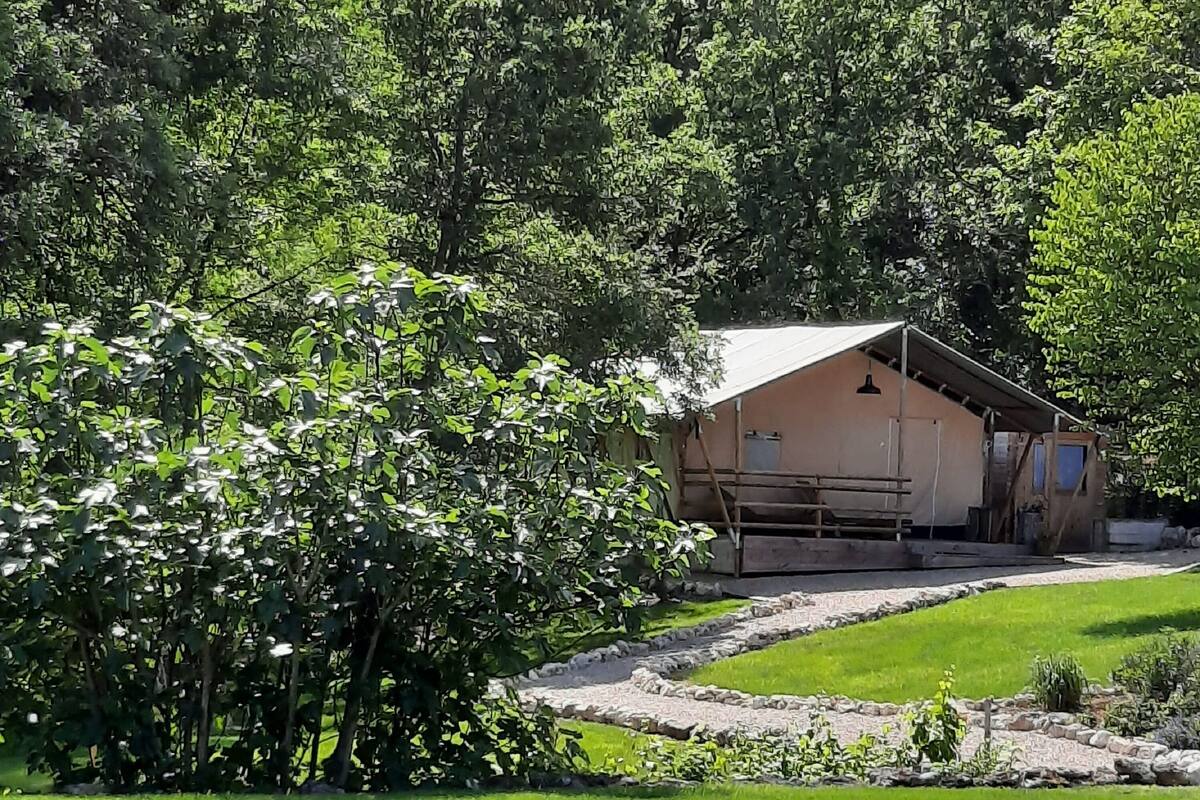 Un chalet rustique, accessible par un sentier de pierres, entouré d’une végétation luxuriante et d’une pelouse bien entretenue.