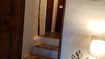 A staircase with wooden steps and a white wall. There is a nightstand with a lamp and a small plant.