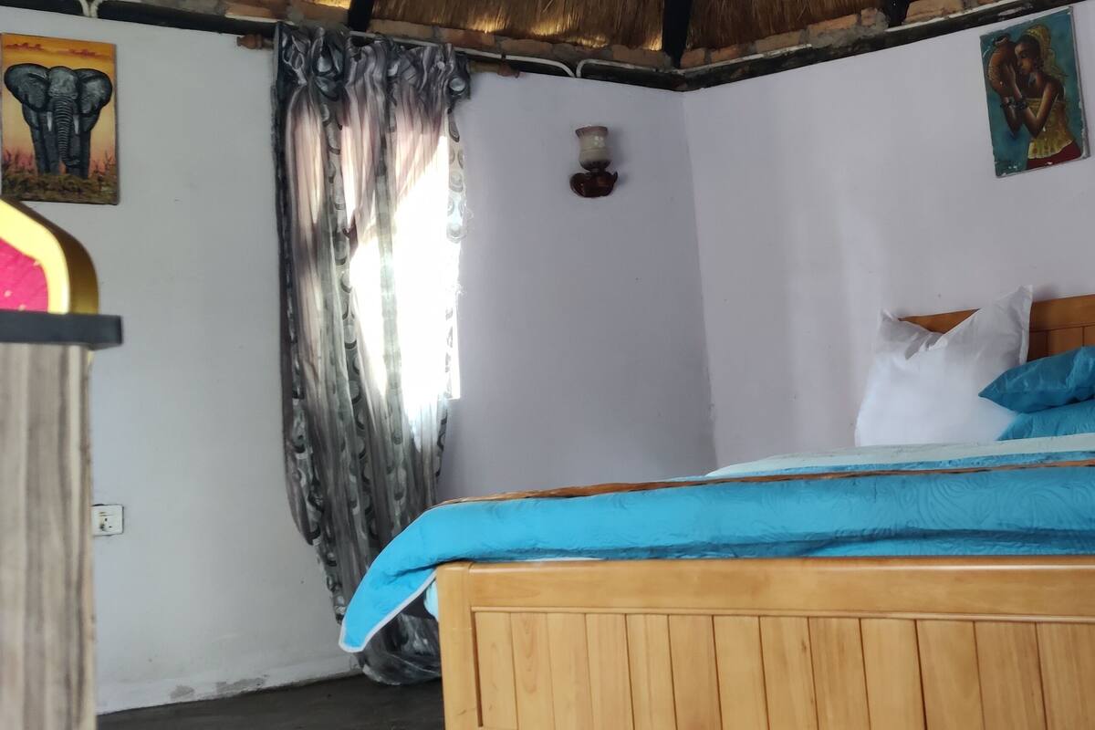 A bedroom with a wooden bed, blue bedding, and two wall-mounted light fixtures.