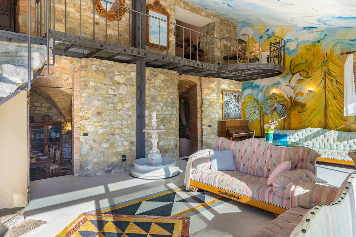 A spacious living area with a stone wall, a piano, a sofa, and a staircase.