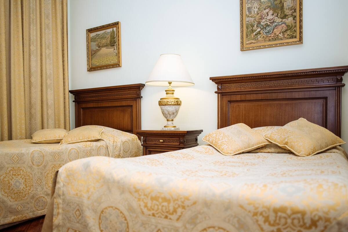 Una habitación de hotel con dos camas, una mesita de noche, una lámpara y un cuadro en la pared.