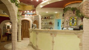 Un área de bar con una barra curva, estantes con botellas y un espejo decorativo.