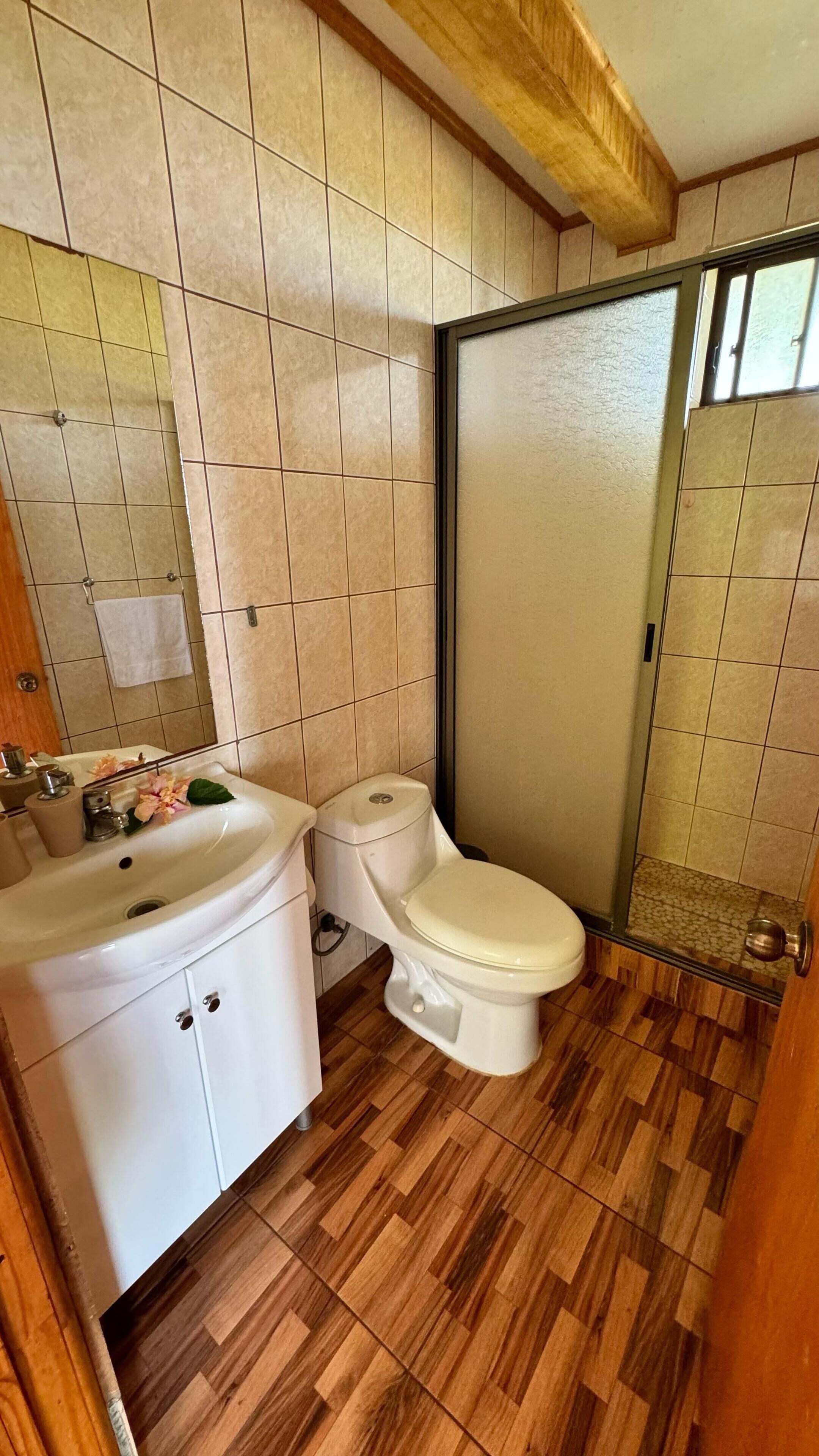 A bathroom with a toilet, sink, and shower area.