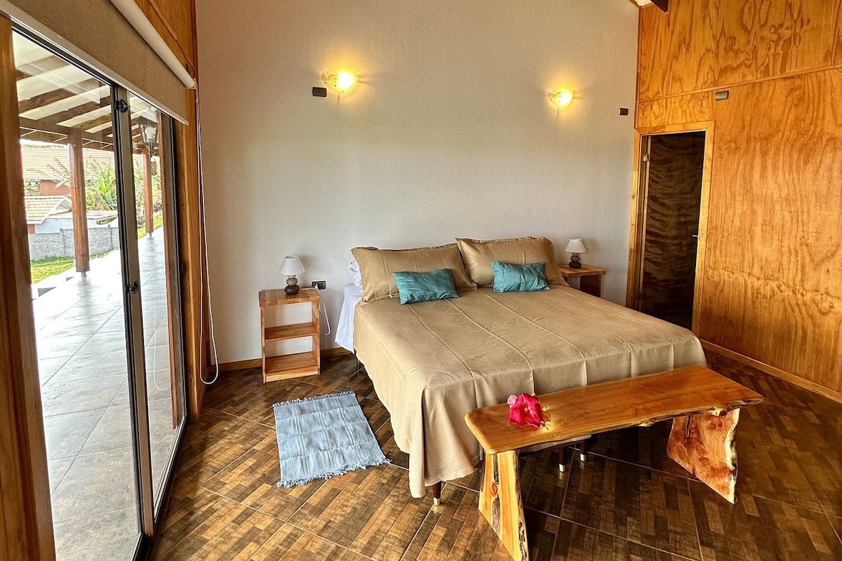 A bedroom with a large bed, wooden floor, and a bench.