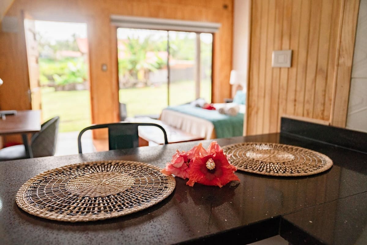 A dining table with woven placemats and a decorative flower centerpiece.
