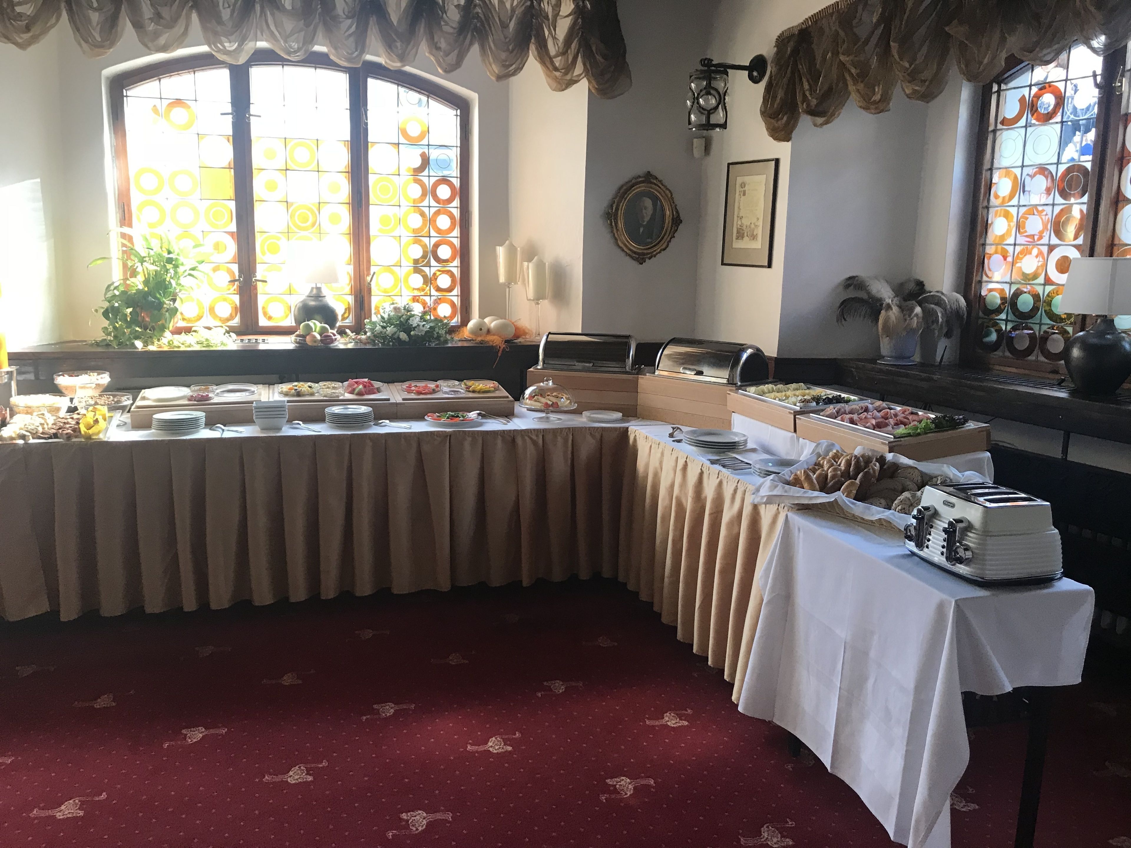 A buffet setup with various food items, a grill, and a decorative window with patterned glass.