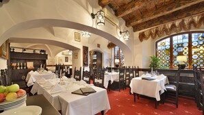 A dining area with tables set for multiple guests, featuring a red carpet and wooden furniture. - Hotel U Tri Pstrosu (Prague)