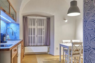 Cozinha compacta com janela, área de jantar com mesa e cadeiras, e uma luminária pendente.