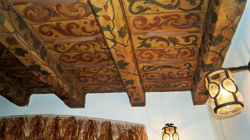 Een plafond met ingewikkelde houtsnijwerken en een hanglamp.