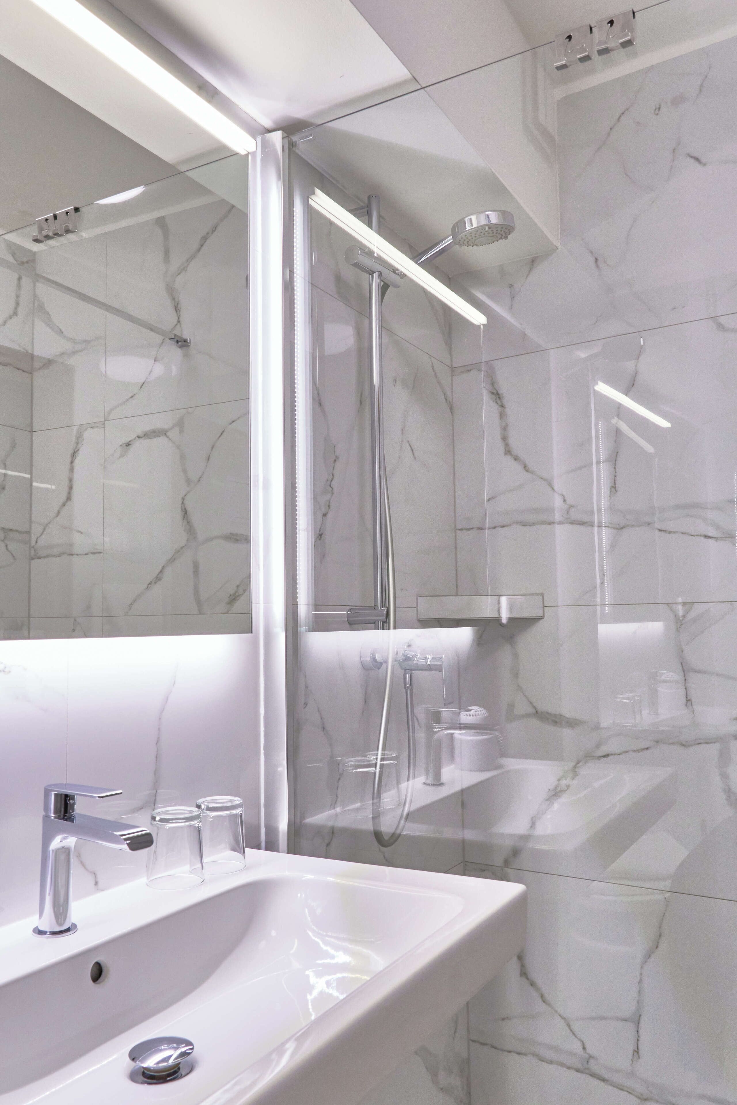 A modern bathroom with a white sink, mirror, and shower.