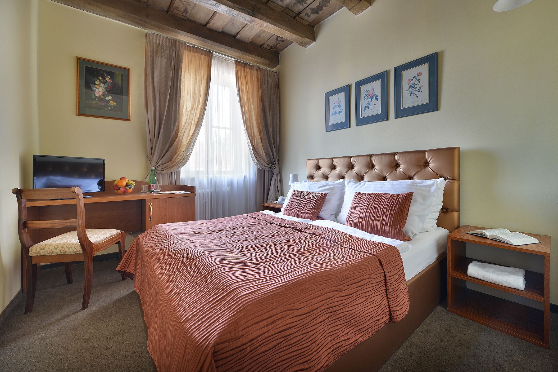 A bedroom with a bed, a desk, a chair, and a nightstand.