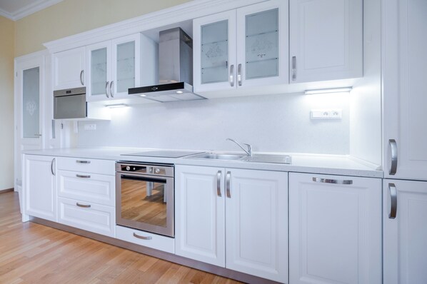 Una cocina moderna con muebles blancos, electrodomésticos de acero inoxidable y horno empotrado.