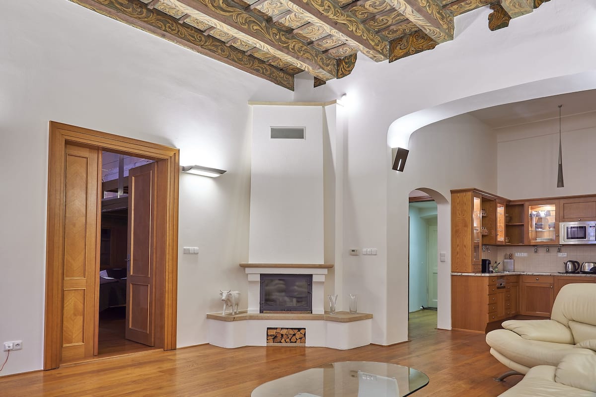 Una sala de estar moderna con chimenea, piso de madera y una zona de cocina con armarios de madera y un microondas.