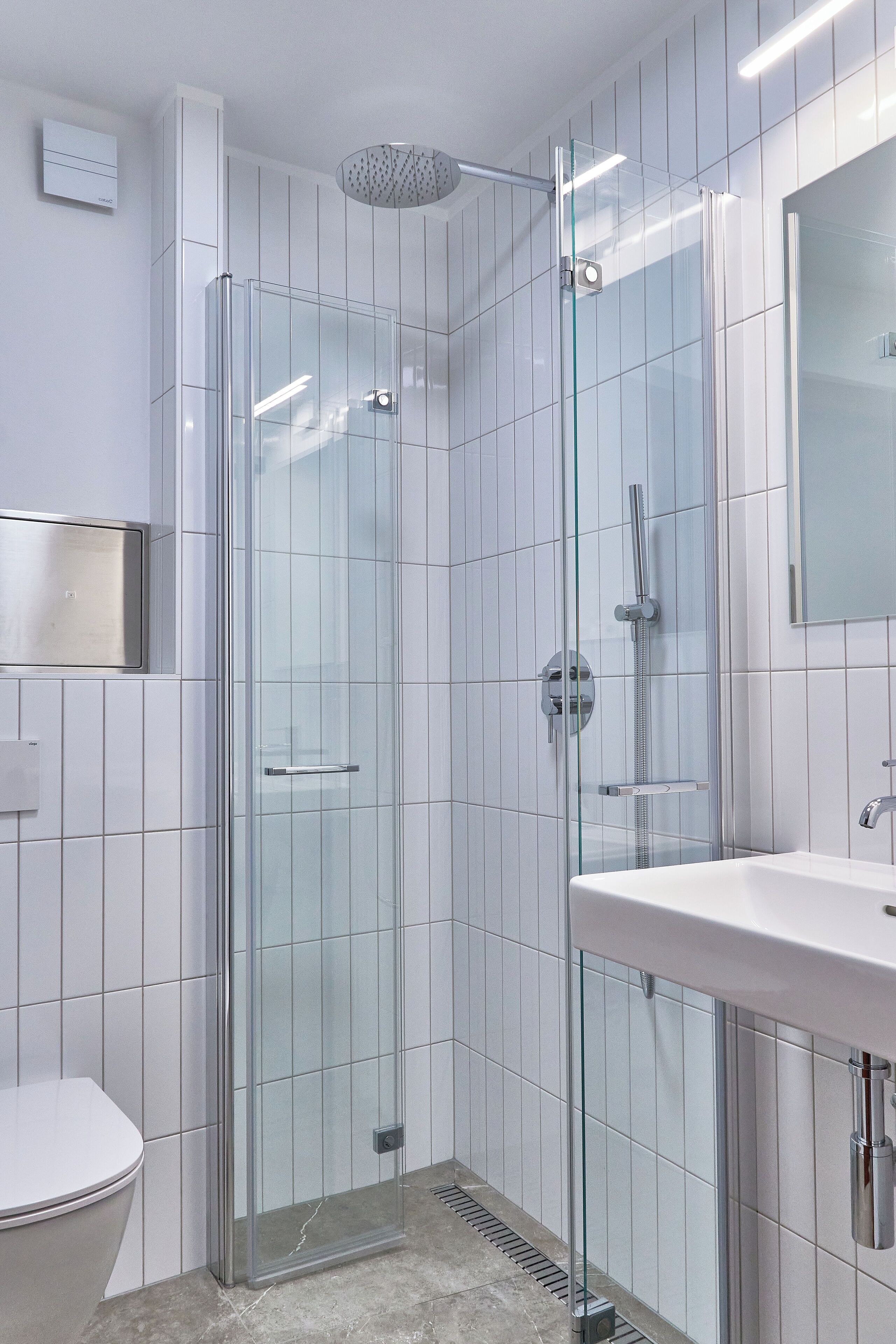 Une salle de bain moderne avec une douche à parois de verre, un lavabo blanc et des toilettes.