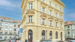 A historic building with a corner tower, large windows, and a sign for a cafe. - Hotel U Tri Pstrosu (Prague)