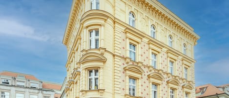 A historic building with a corner tower, large windows, and a sign for a cafe.