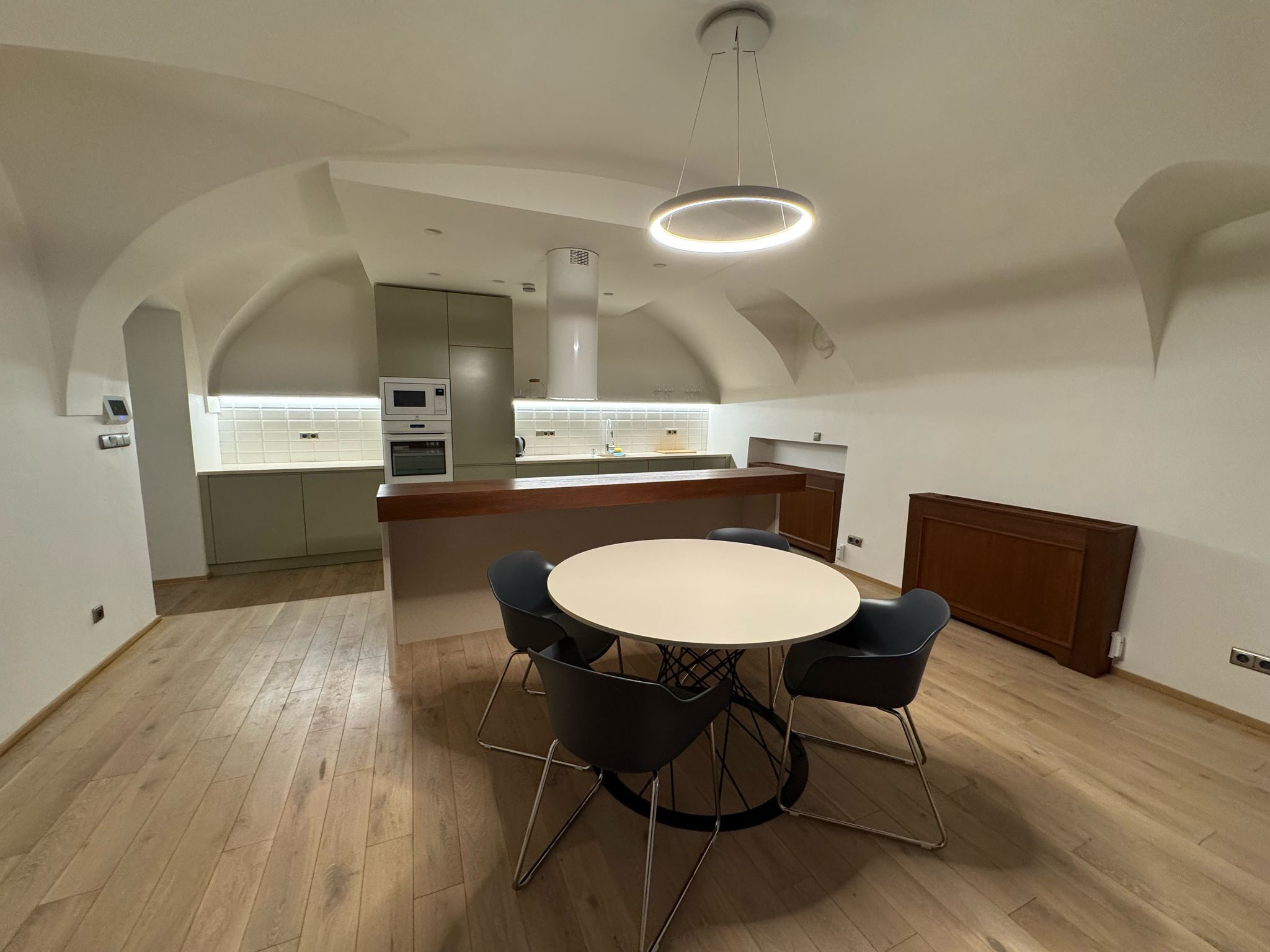 Una cocina moderna con una isla central, electrodomésticos integrados y un comedor con una mesa redonda y sillas.