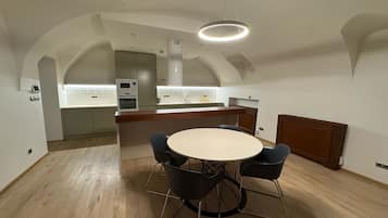 Una cocina moderna con una isla central, electrodomésticos integrados y un comedor con una mesa redonda y sillas.