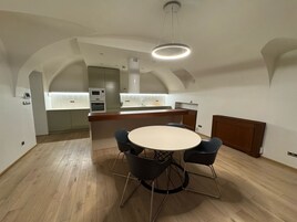 A modern kitchen with a central island, built-in appliances, and a dining area with a round table and chairs.