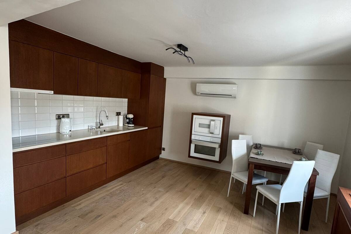 Una cocina moderna con armarios de madera, una encimera blanca y un comedor con mesa y sillas.