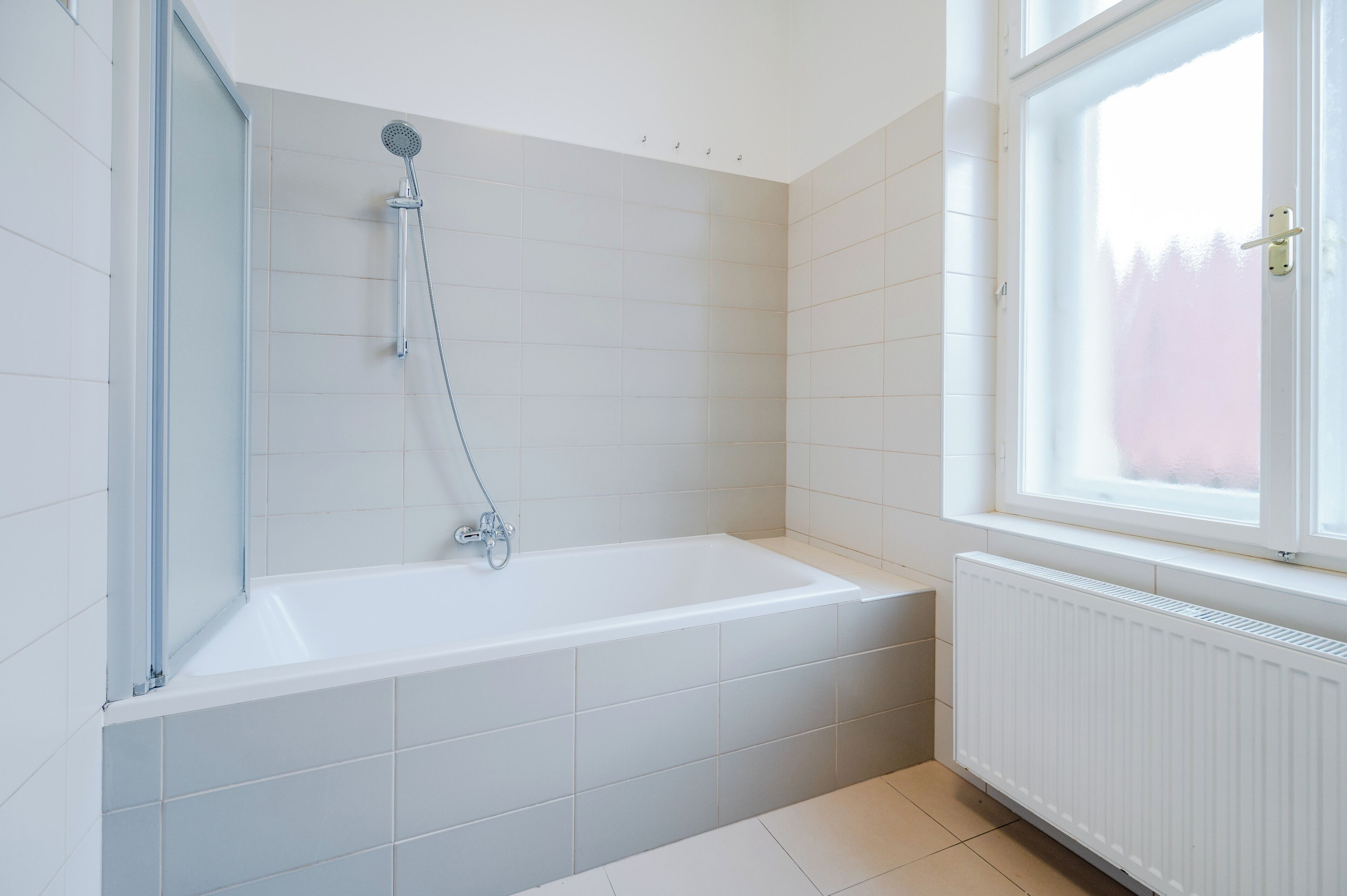 A modern bathroom with a bathtub, a shower, and a window.