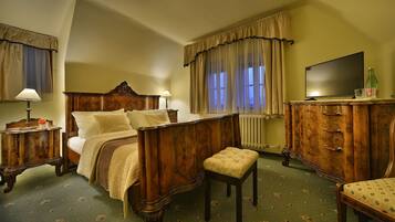 Une chambre à coucher avec un lit en bois, une table de chevet, une commode, un téléviseur et une fenêtre avec des rideaux.