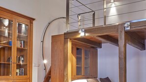 A loft-style bedroom with exposed wooden beams, a bunk bed, a wooden cabinet with glass doors, and a staircase. - Hotel U Tri Pstrosu (Prague)