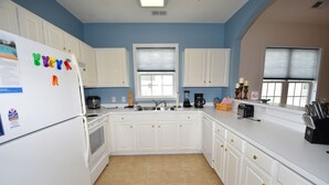 A kitchen with white cabinets, a refrigerator, a sink, and a coffee maker. - Ironwood Apartment 1631 (North Myrtle Beach)