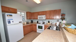 A kitchen with wooden cabinets, a white refrigerator, a microwave, a stove, and a sink.