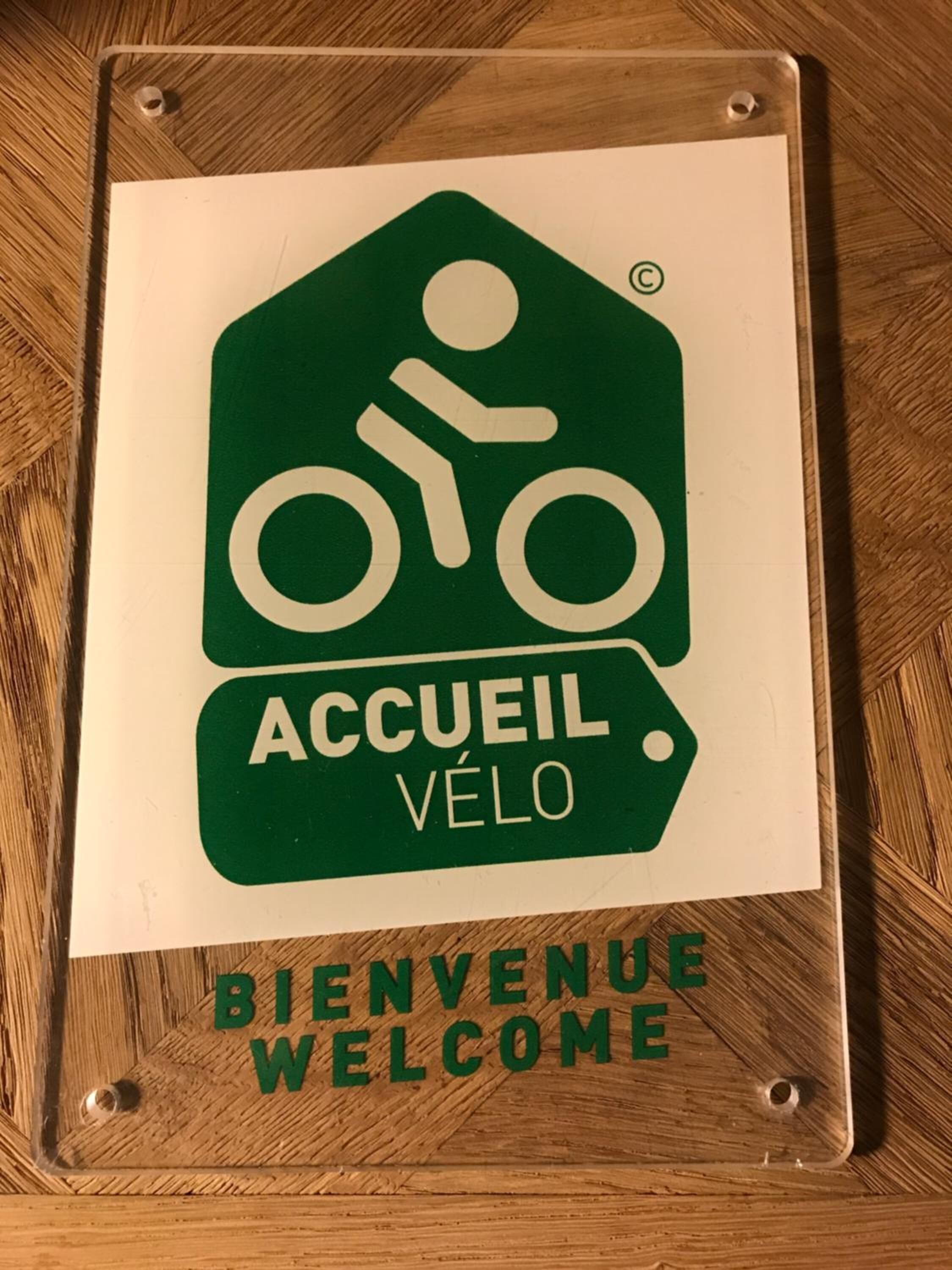 Letrero de bienvenida con un símbolo de bicicleta y el texto 'ACCUEIL VÉLO', que indica un alojamiento para ciclistas.