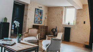 Un salon avec une cheminée, un tableau et une vue sur l’extérieur.
