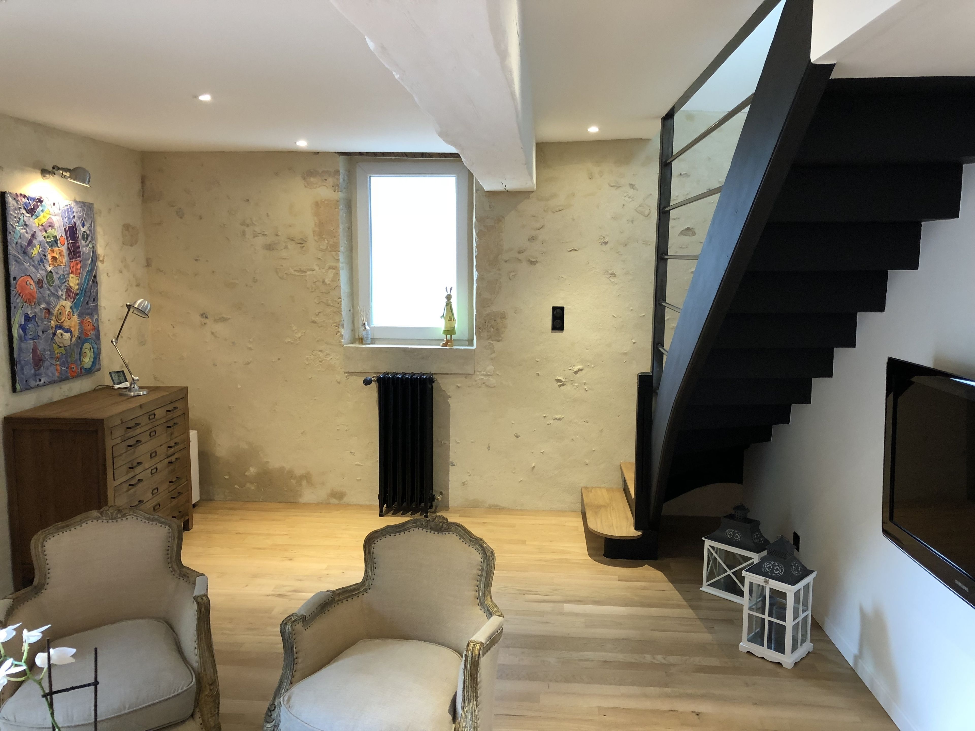 Un espacio habitable amplio con un techo alto, una escalera moderna y un gran ventanal que proporciona luz natural.