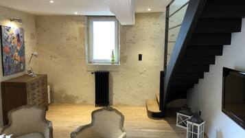 Un espacio habitable amplio con un techo alto, una escalera moderna y un gran ventanal que proporciona luz natural.