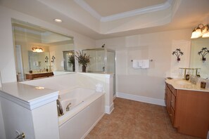 A modern bathroom with a large bathtub, a glass-enclosed shower, and a vanity with a sink and mirror.