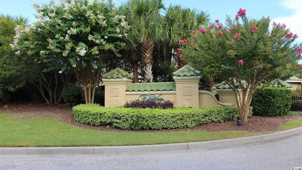 A landscaped area with a variety of trees and shrubs, a sign with the name 'Fairwater', and a curved pathway leading to a building. - Edgewater Apartment 437 (North Myrtle Beach)