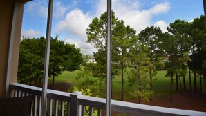 A view from a balcony with a railing, overlooking a grassy area with trees and a building in the distance. - Edgewater Apartment 437 (North Myrtle Beach)