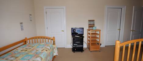 Un dormitorio con dos camas de madera, un televisor y una estantería.