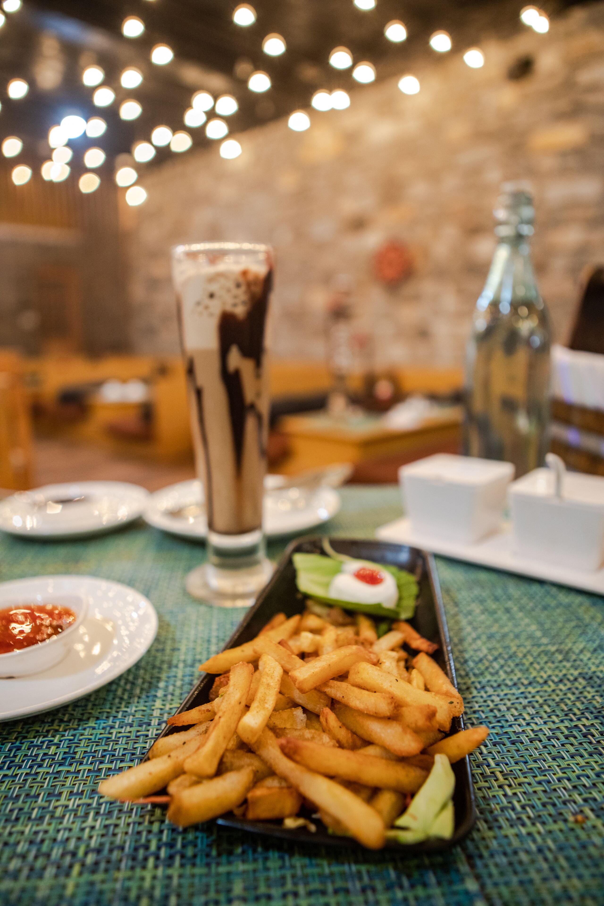 Una mesa de comedor con una porción de papas fritas, un batido y una botella de agua.