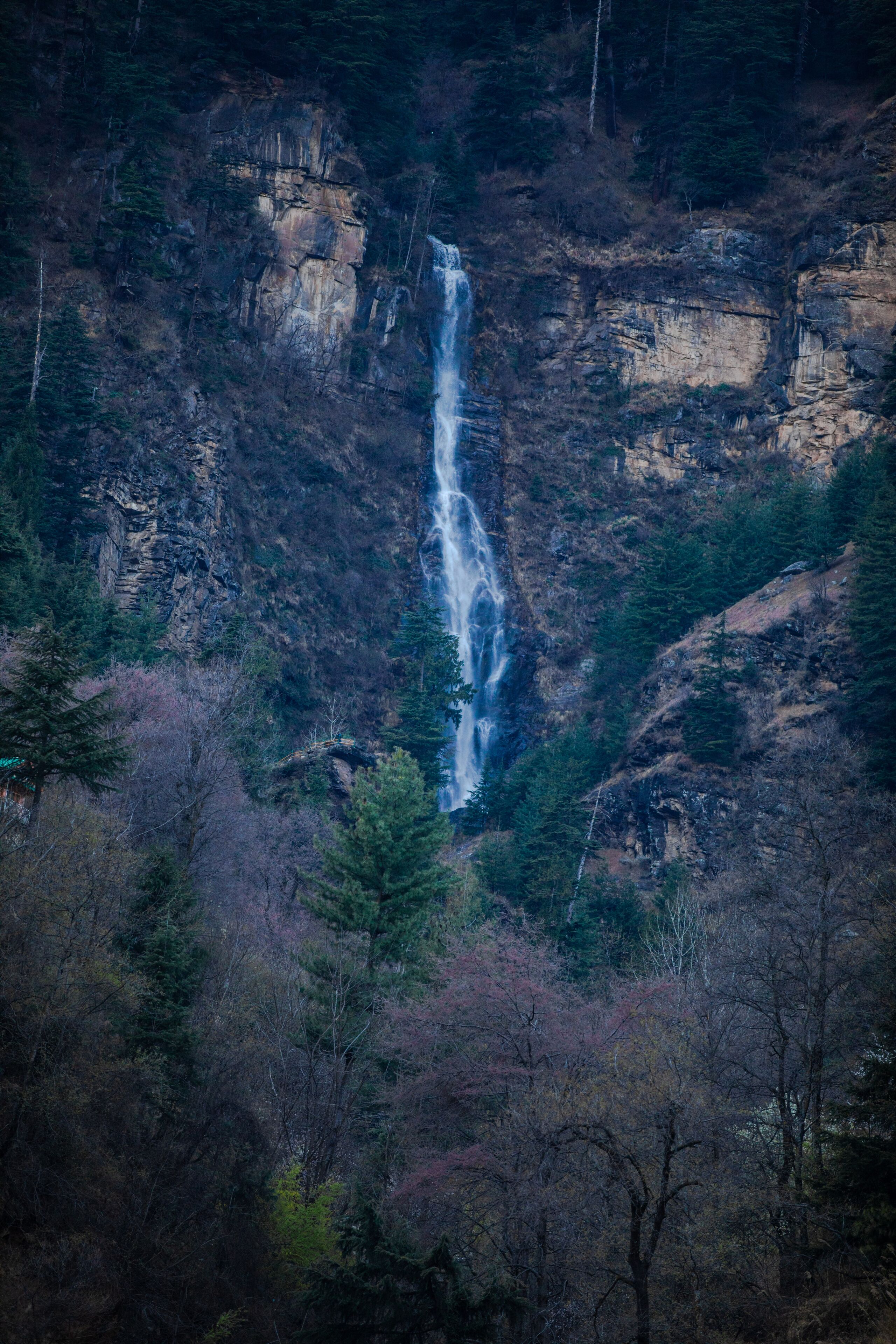 A waterfall cascading down a rocky cliff surrounded by trees.