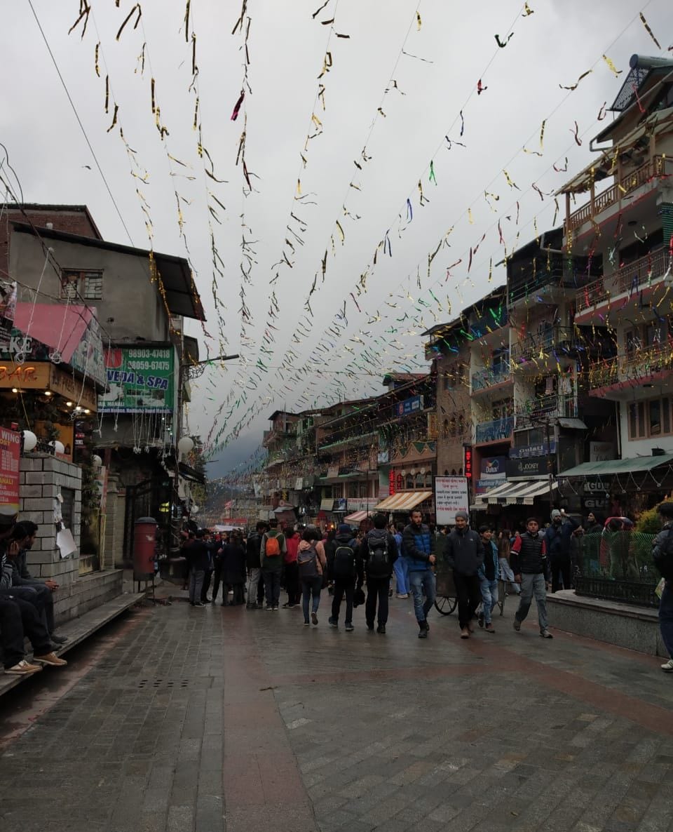 A crowded street with shops and balconies, decorated with hanging streamers.