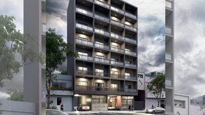 A multi-story hotel with a modern design, featuring balconies on each floor and a prominent entrance with a sign.