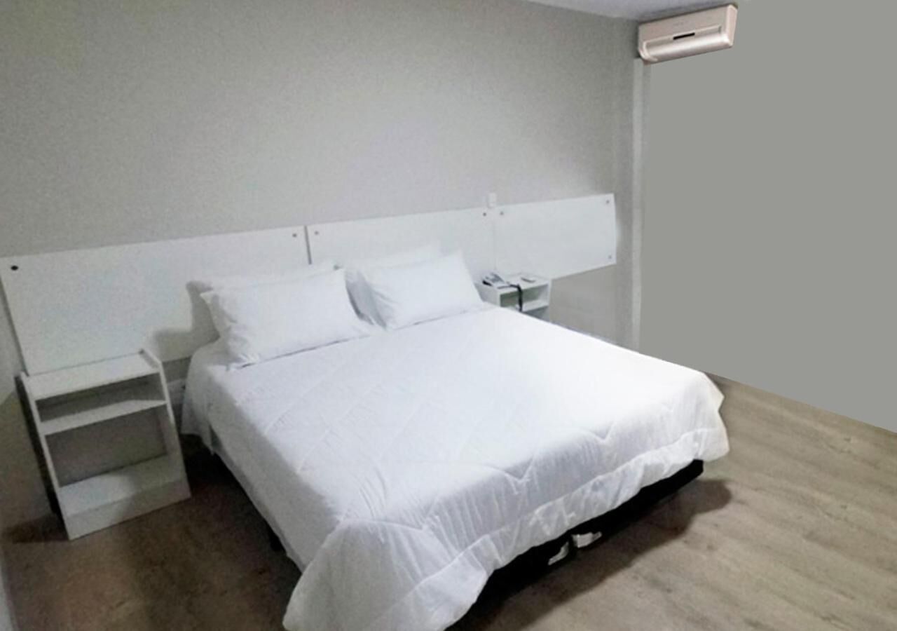 A neatly made bed with white bedding in a room with a simple, clean design.