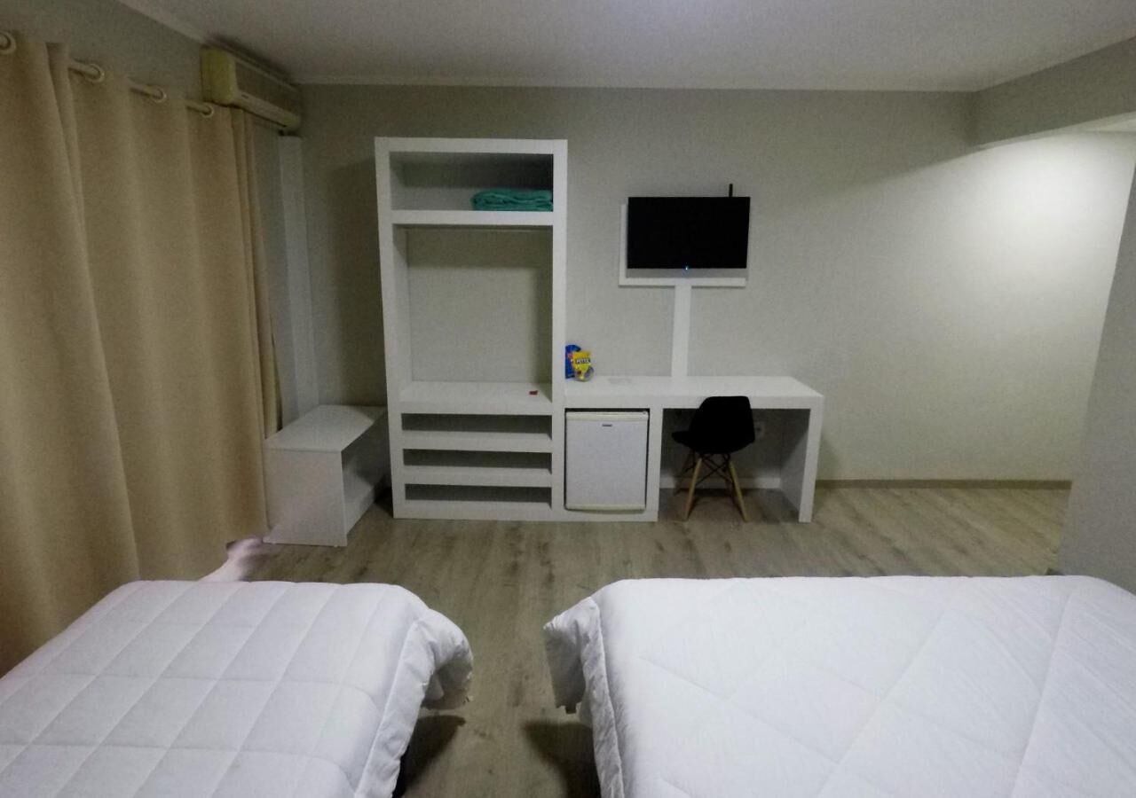 A hotel room with two beds, a desk, a TV, and a wardrobe.