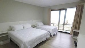 A hotel room with two beds, a large window, and a view of the city.