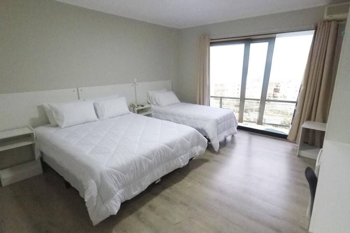 A hotel room with two beds, a large window, and a view of the city.